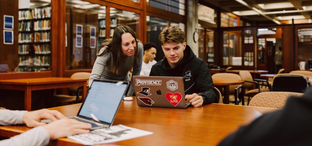 Student working on computer being helped by someone else